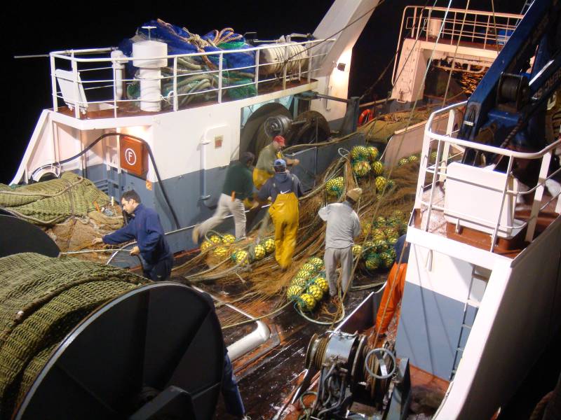 Fishermen rolling up the nets in a pelagic trawler in the port of Muxia, Spain. August 2007.